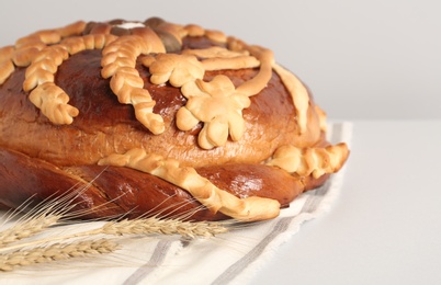 Korovai with wheat spikes on white table, closeup. Ukrainian bread and salt welcoming tradition