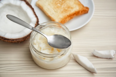 Jar with coconut oil and fresh toast on wooden background