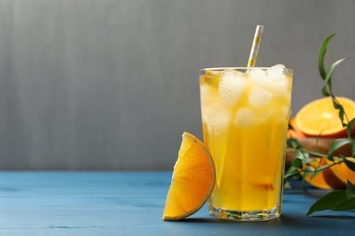 Delicious orange soda water on blue wooden table. Space for text