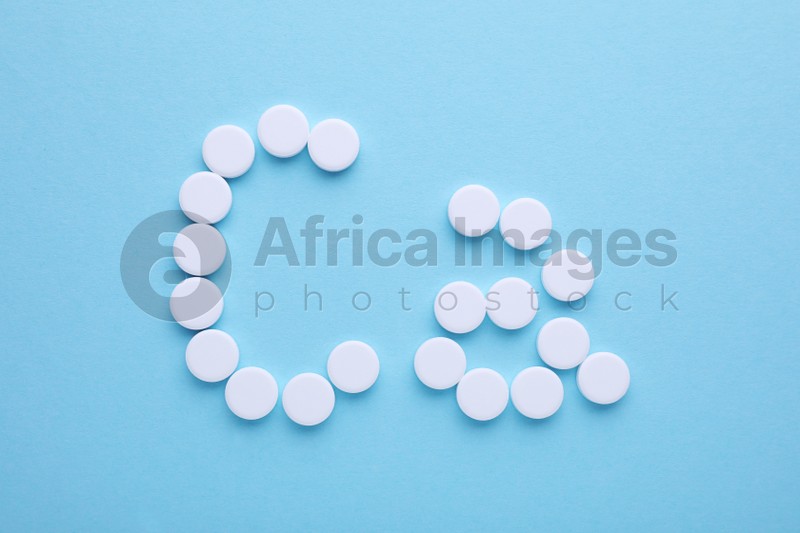 Photo of Calcium symbol made of white pills on light blue background, flat lay