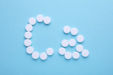 Calcium symbol made of white pills on light blue background, flat lay