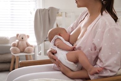 Young woman breastfeeding her little baby at home, closeup. Space for text