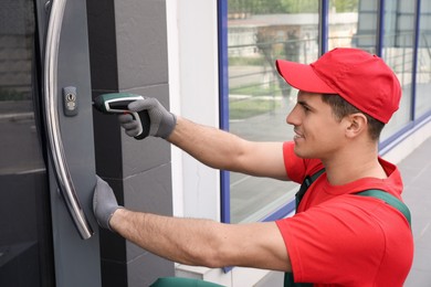 Handyman with screw gun repairing door lock outdoors