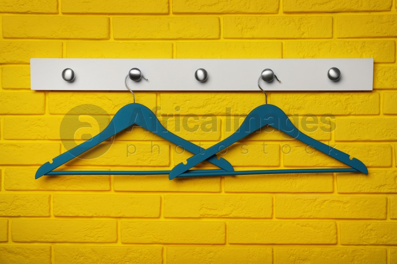 Photo of Rack with clothes hangers on yellow brick wall