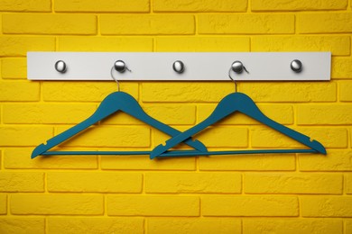 Rack with clothes hangers on yellow brick wall