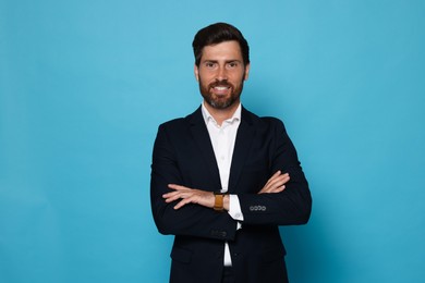 Portrait of handsome bearded man in suit on light blue background