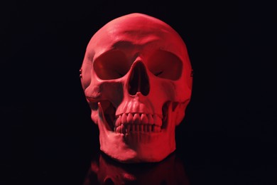 Red human skull with teeth on black background
