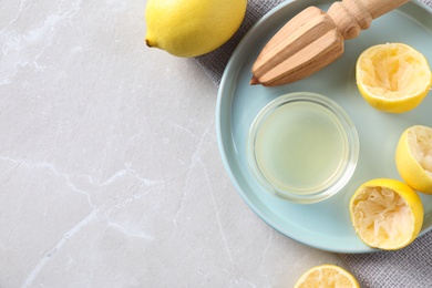 Photo of Flat lay composition with fresh lemons, juice and reamer on grey marble table. Space for text