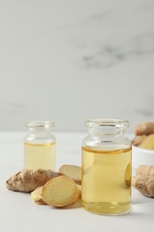 Photo of Glass bottle of essential oil and ginger root on white table
