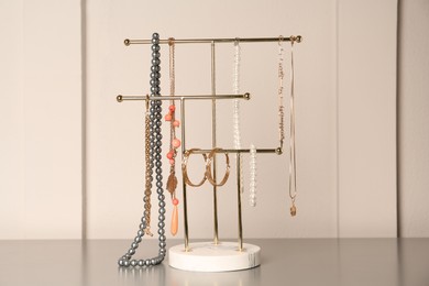 Holder with set of luxurious jewelry on grey table
