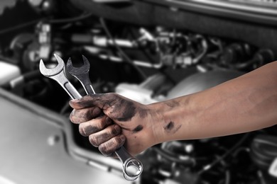 Image of Auto mechanic with wrench near broken down car, closeup