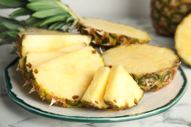 Photo of Plate with tasty cut pineapple on table, closeup