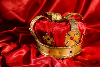 Photo of Beautiful velvet crown on red fabric. Fantasy item