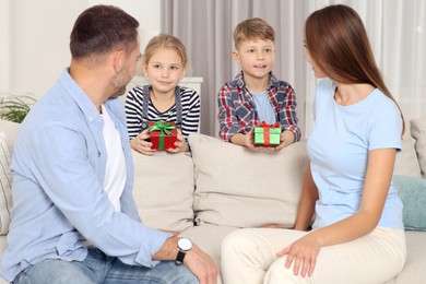 Little children presenting their parents with gifts at home