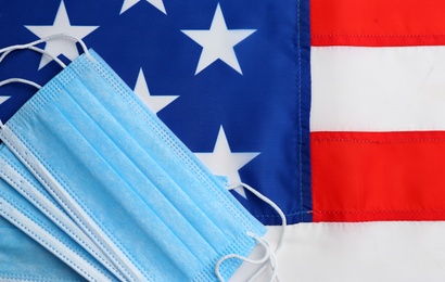 Medical masks on American flag, flat lay. Coronavirus pandemic in USA