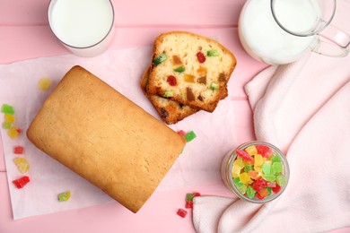 Delicious cake with candied fruits and milk on pink wooden table, flat lay