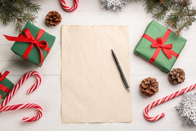 Flat lay composition with paper and Christmas decor on white wooden table. Writing letter to Santa Claus