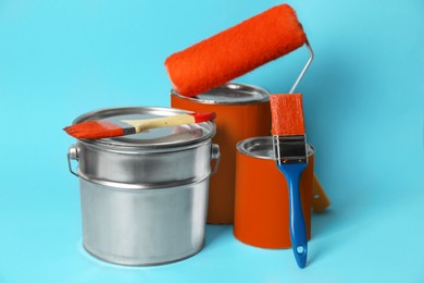 Photo of Cans of paint, bucket, roller and brushes on turquoise background