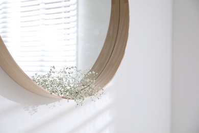 Photo of Beautiful flowers on modern round mirror indoors