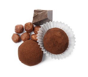 Delicious chocolate truffles with ingredients on white background, top view