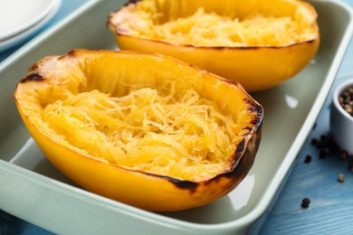 Halves of cooked spaghetti squash in baking dish on table, closeup