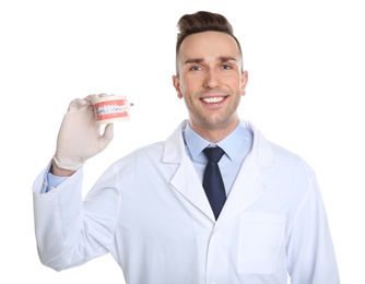Male dentist holding model of oral cavity with teeth on white background