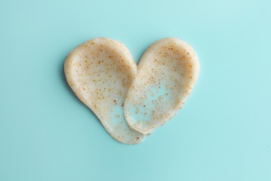 Samples of face scrub in shape of heart on light blue background, top view