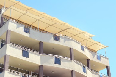 Exterior of beautiful residential building with balconies against blue sky