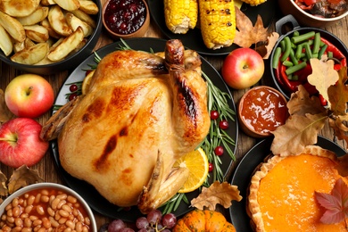 Traditional Thanksgiving day feast with delicious cooked turkey and other seasonal dishes served on wooden table, top view