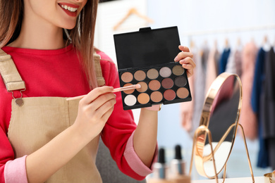 Beauty blogger with brush and eyeshadow palette at home, closeup