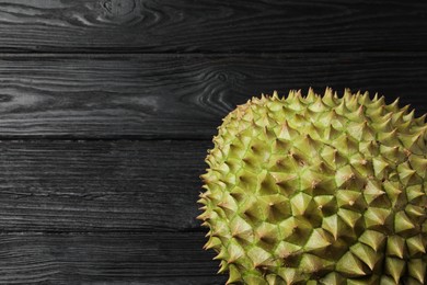 Ripe durian on black wooden table, top view. Space for text
