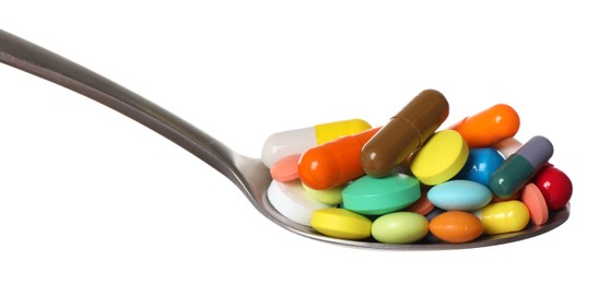 Different colorful pills in spoon isolated on white