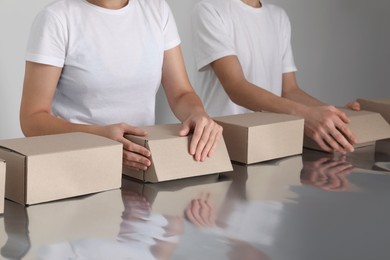 Workers folding cardboard boxes at table, closeup. Production line 