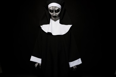 Portrait of scary devilish nun on black background. Halloween party look