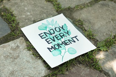 Card with phrase Enjoy Every Moment on ground