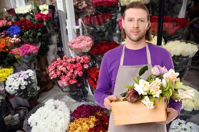 Image of Florist holding basket with flowers in shop 