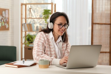 Woman with modern laptop and headphones learning at home