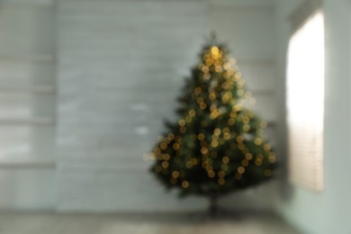 Blurred view of Christmas tree in empty room, space for text. Bokeh effect