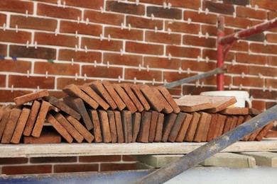 Many decorative bricks on scaffolding near wall. Tiles installation process