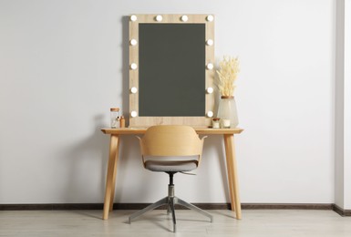Photo of Dressing table with stylish mirror, dried reeds and other decorative elements. Interior design
