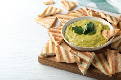 Photo of Delicious pita chips and hummus on white wooden table, closeup