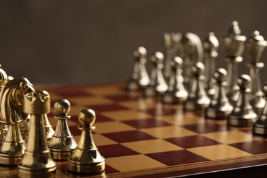 Chessboard with game pieces on grey background, closeup