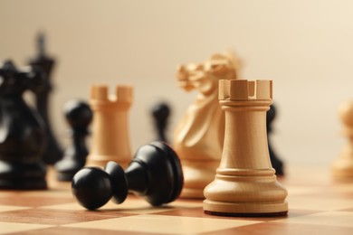 Chessboard with game pieces on beige background, closeup