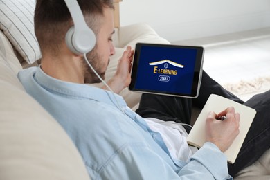 Young man with headphones using modern tablet for studying at home, closeup. E-learning
