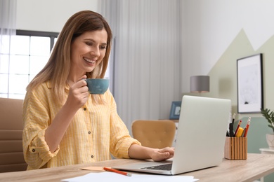 Young woman working with laptop at desk in home office