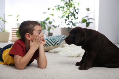 Little boy with puppy on floor at home. Friendly dog
