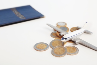 Toy plane with coins on white background. Travel insurance