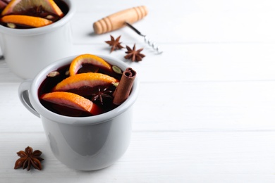 Aromatic mulled wine on white wooden table. Space for text