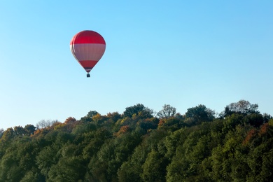 Beautiful view of hot air balloon flying over autumn forest. Space for text