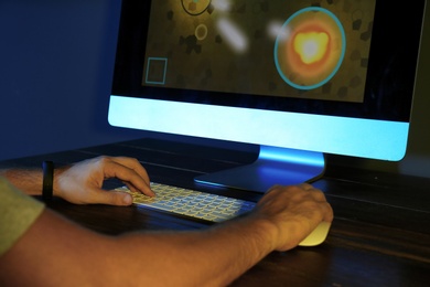 Man playing video game on modern computer in dark room, closeup